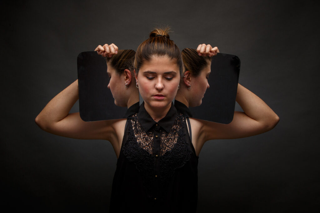 Modern model holding mirrors on sides of face