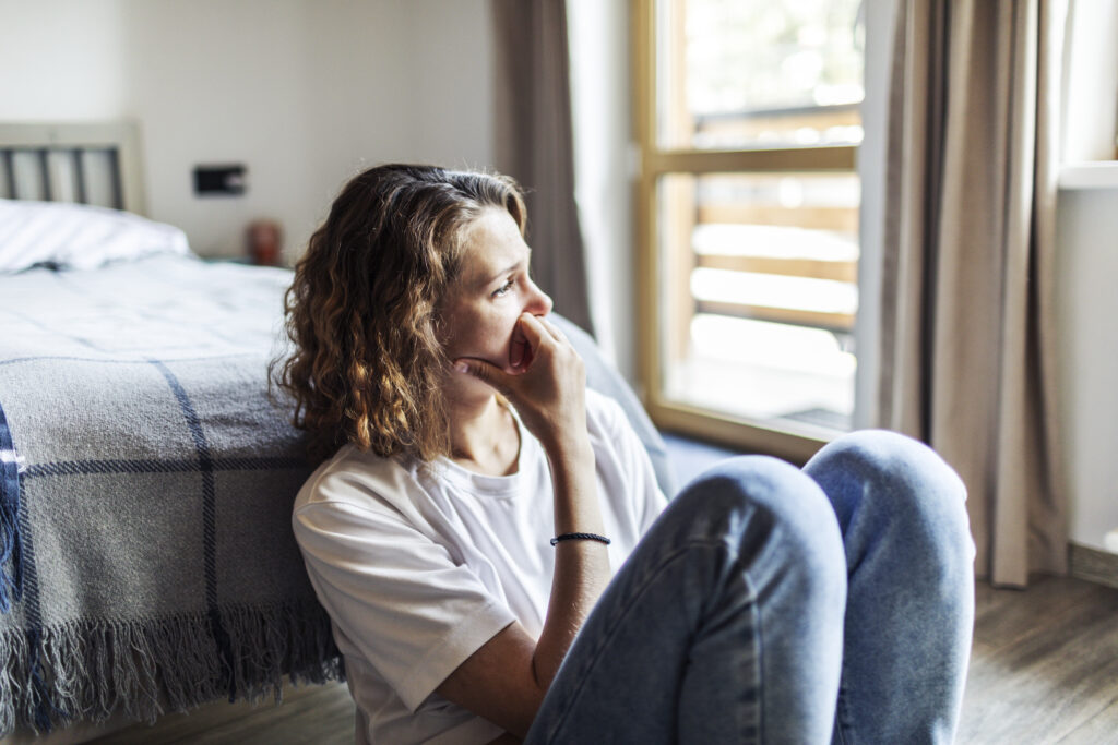 Young adult woman with depression sitting at home alone thinking if she should look into an outpatient program